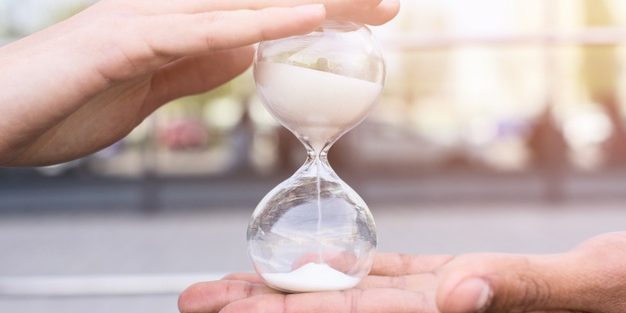 close-up-person-s-hand-holding-hourglass_23-2148192519